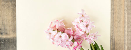 Pink hyacinth flowers and empty card on wooden table. greeting card. Spring coming concept. Spring...
