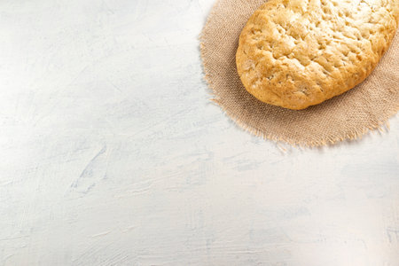 Italian focaccia or Italian bread.Fresh, tasty bread with aromatic herbs on napkin on white textured...