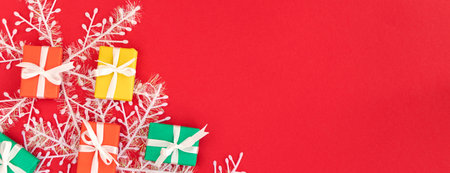 banner with red, green and yellow gifts on a redbackground with space for text. Colorful scattered...