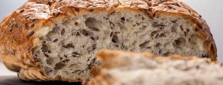 banner with close up sliced bread on serving board with flax and sunflower seeds. Fresh, tasty, round wheat bread with flax seeds on a white textured table with space for text. Soft focusの写真素材
