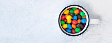 banner with multi-colored chocolates in the form of eggs in a white mug on a white background. top viewの写真素材