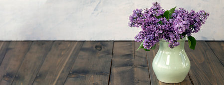 banner with lilac branches in a clay vase on a wooden background. Beautiful lilac flowers. Spring blossom. spring or summer concept. lilac flowers with place for text.の写真素材