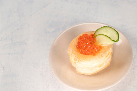 top view of appetizer with red caviar. Tartlets, red caviar, cucumber on a white background with space for your text. Delicious and healthy snack. Copy spaceの写真素材