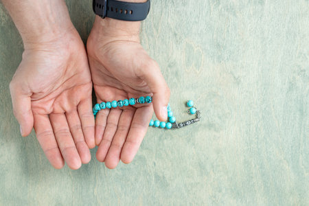 top view on male hands holding rosary beads. Ramadan Kareem background. Muslim man holds a rosary. Flat lay. copy spaceの写真素材
