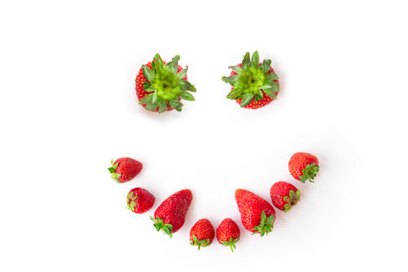 juicy, ripe strawberries on a white background. Strawberry in the shape of a smiling face with fangs. funny or scary face made of berries. isolated. flat lay.の写真素材