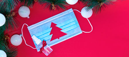 banner with blue medical protective mask with cut-out silhouette of Christmas tree and sanitizer...