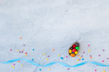 candy in the shape of an egg filled with multi-colored chocolates on a white textured background...