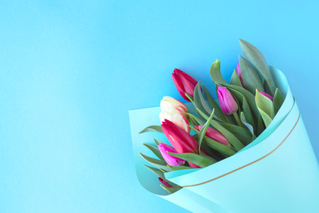 Multicolored bouquet of tulips on a blue background. concept of spring and holiday, mothers day or March 8. copy space, top view, flat lay, creative,の写真素材