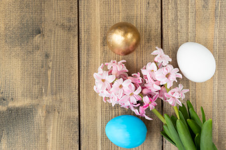 blue, white and golden eggs and pink hyacinth flowers on wooden table. Happy Easter concept. Easter background Top viewの写真素材