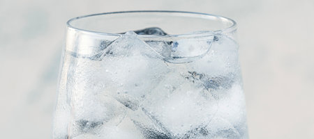 banner with close up glass with ice water and ice cubes on white textured background. A refreshing and chilling drink in hot weather. soft focusの写真素材