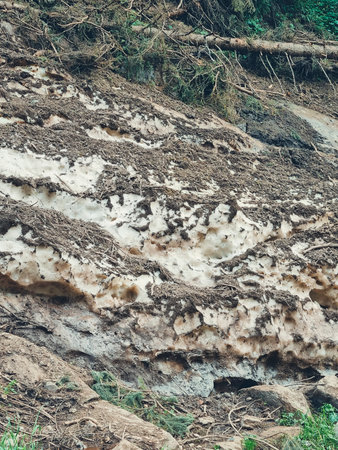 Vertical photo of a snow patch remaining in summer with a small area of green grass visible at the edge.の写真素材