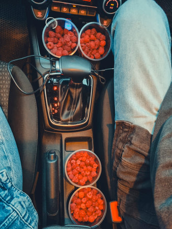 Vertical photo, top view of a car dashboard with four transparent glasses filled with ripe red...