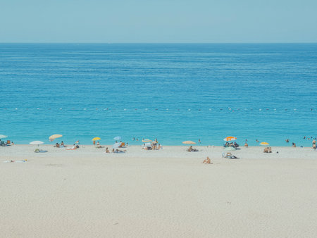 Photo of a beach with bright umbrellas on light sand, two-thirds filled with turquoise sea and sky, resembling a watercolor artwork in Turkey.の写真素材