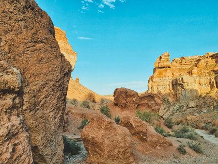 Rock formations of various shapes in Charyn Canyon, ranging in color from pale yellow to deep orange under natural light.の写真素材
