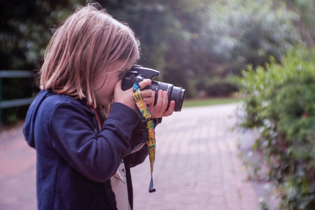Joyful young girl taking photos with child photo digital camera outdoor
