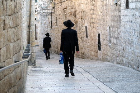 Two unrecognized religious jewish men walking down the street in Old City of Jerusalem.のeditorial素材