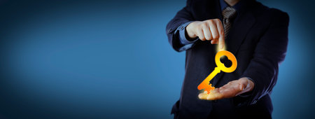 Unrecognizable businessman in blue is pointing at a virtual key that he is holding in his open palm. Business concept for turnkey solution, leadership, knowledge, consulting and customer services.の写真素材