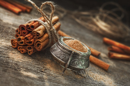 Ground cinnamon, cinnamon sticks, tied with jute rope on old wooden background in rustic styleの写真素材