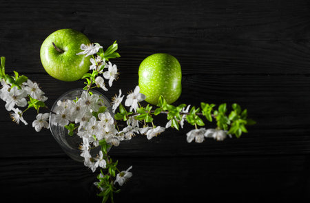 Green apples with blossoms on wooden tableの写真素材