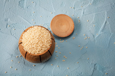 Sesame seeds in bowl on dark stone background copy space