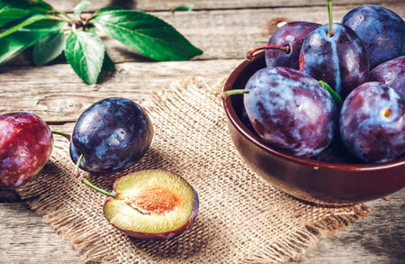 Blue and violet plums on wooden tableの写真素材