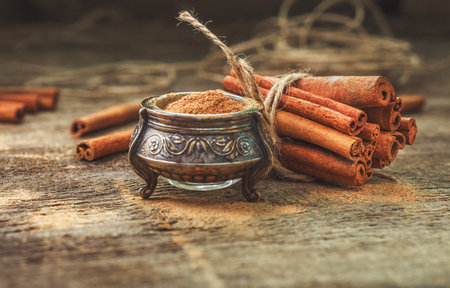 Ground cinnamon, cinnamon sticks, tied with jute rope on old wooden background in rustic style.の写真素材
