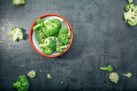 Fresh raw broccoli in a wooden bowl on a dark background.Top view. Free space.の写真素材