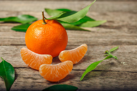 Tangerines (oranges, clementines, citrus fruits) with green leaves over wooden background with copy spaceの写真素材