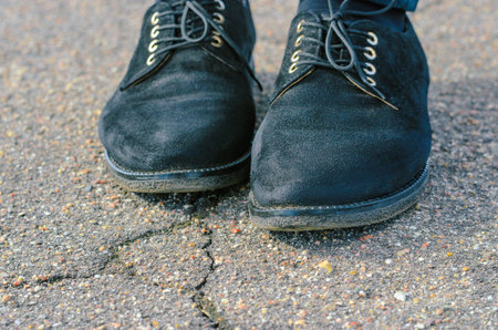 Old Black Female Shoes with Asphalt Background. Female feet standing on roadの写真素材