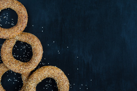 Turkish simit bagel dusted with sesame seeds on a black background. Top view. Banner background with copy spaceの写真素材
