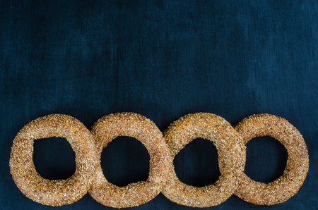Turkish simit bagel dusted with sesame seeds on a black background. View from above. Banner...