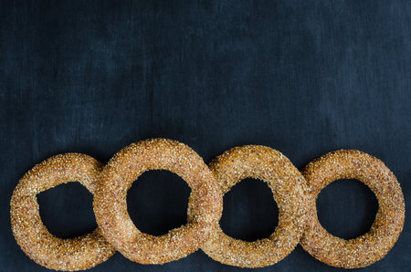 Turkish simit bagel dusted with sesame seeds on a black background. Top view. Banner background with copy spaceの写真素材