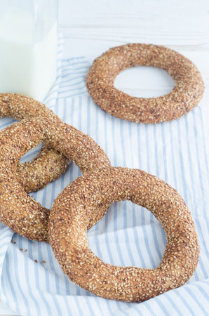 Turkish simit bagels with sesame, a bottle of milk and a glass on a wooden table. Cotton fabric and blur backgroundの写真素材