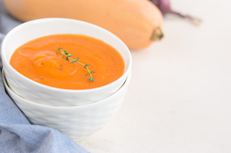 Pumpkin cream soup on a white table. Shallot Thyme Napkin Pumpkin. Copy spaceの写真素材