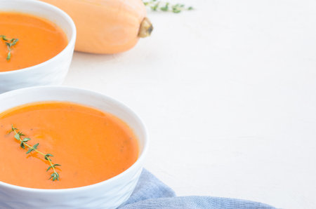 Pumpkin cream soup on a white table. Thyme Napkin Pumpkin. Copy spaceの写真素材