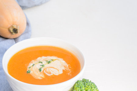 Pumpkin cream soup on a white table. Thyme Broccoli Pumpkin. Copy spaceの写真素材
