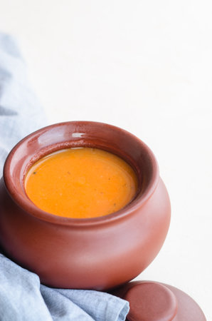 Pumpkin cream soup in a ceramic bowl on a white table. Napkin. Copy spaceの写真素材