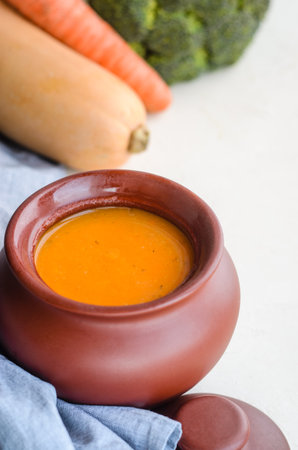 Pumpkin cream soup in a ceramic bowl on a white table. Napkin Garlic Carrot Broccoli Pumpkin. Copy spaceの写真素材