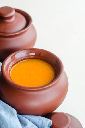 Pumpkin cream soup in a ceramic bowl on a white table. Napkin. Copy spaceの写真素材