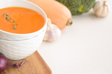 Pumpkin cream soup on a white table. Board Shallot Thyme Garlic Napkin Broccoli Pumpkin. Copy spaceの写真素材