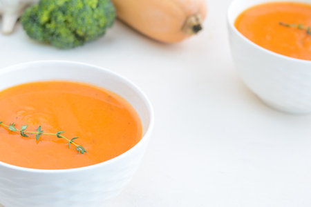 Pumpkin cream soup on a white table. Thyme Garlic Broccoli Pumpkin. Copy spaceの写真素材