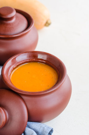 Pumpkin cream soup in a ceramic bowl on a white table. Napkin Pumpkin. Copy spaceの写真素材