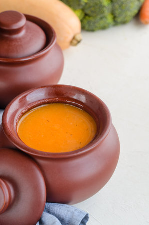 Pumpkin cream soup in a ceramic bowl on a white table. Napkin Garlic Carrot Broccoli Pumpkin. Copy spaceの写真素材
