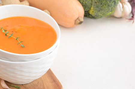 Pumpkin cream soup on a white table. Board Thyme Garlic Napkin Broccoli Pumpkin. Copy spaceの写真素材