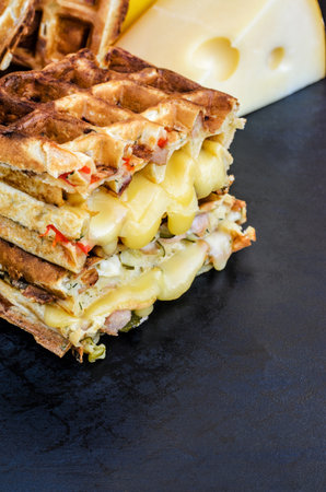 Traditional belgian waffles with cheese and vegetables on a black background. Ham. Mushrooms. Tomato. Cheese. Pepper. Copy space. Closeupの写真素材