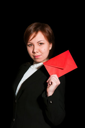Pretty young business woman smiles and holds blank envelope isolated on black