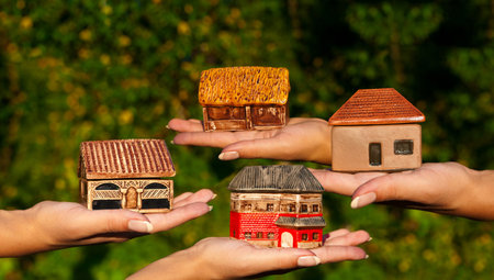 Four different houses in human hands outdoors. Concept of choiceの写真素材