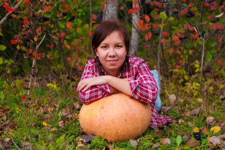 Girl lying with a large pumpkin in the gardenの写真素材