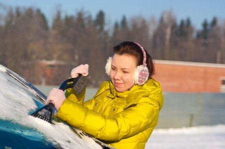 Girl cleaning car windows from snowの写真素材