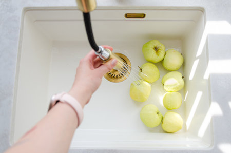 Organic green Antonovka apples washed in sink. Farm fruit in bright kitchen.の写真素材